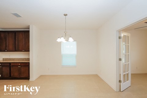 an empty living room with a kitchen and a chandelier