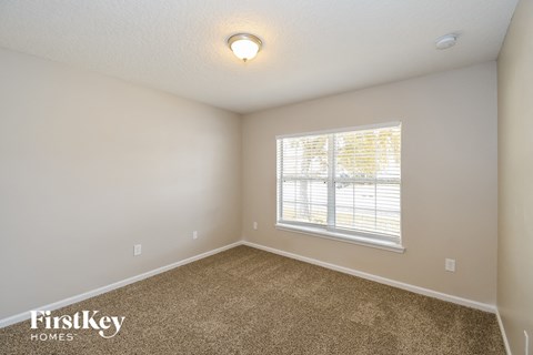 a bedroom with carpet and a large window