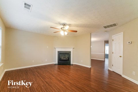 A spacious living room with a fireplace and a ceiling fan.