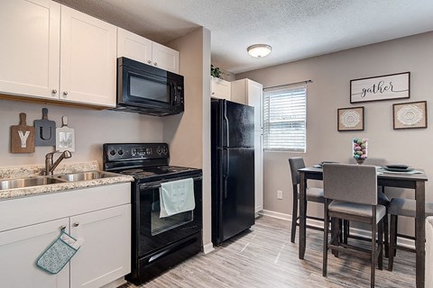 a kitchen with a black refrigerator and a table and chairs