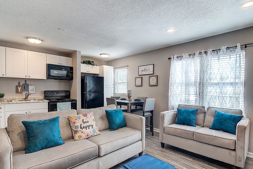 a living room and kitchen with a couch and a chair