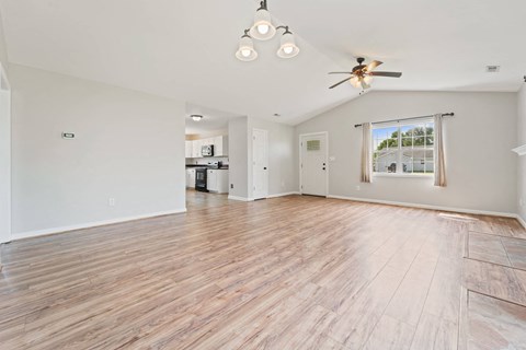 A spacious room with wooden flooring and a ceiling fan.
