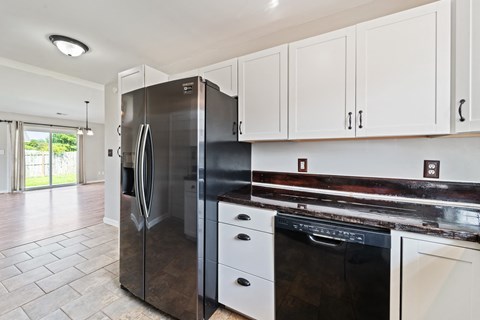 A modern kitchen with a stainless steel refrigerator and white cabinets.