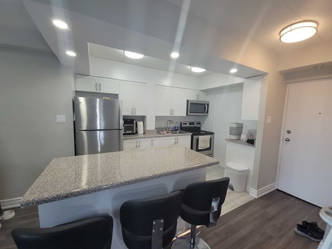 A kitchen with a granite countertop and black chairs.