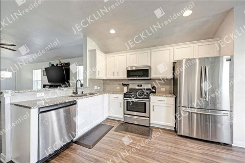 a large kitchen with stainless steel appliances and white cabinets