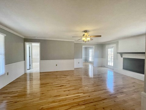 A spacious room with wooden floors and a fireplace.