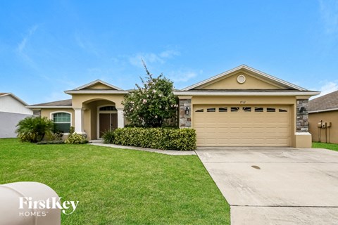 a yellow house with a driveway and a garage door