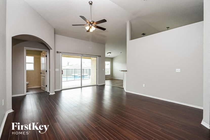 an empty living room with wood floors and a ceiling fan