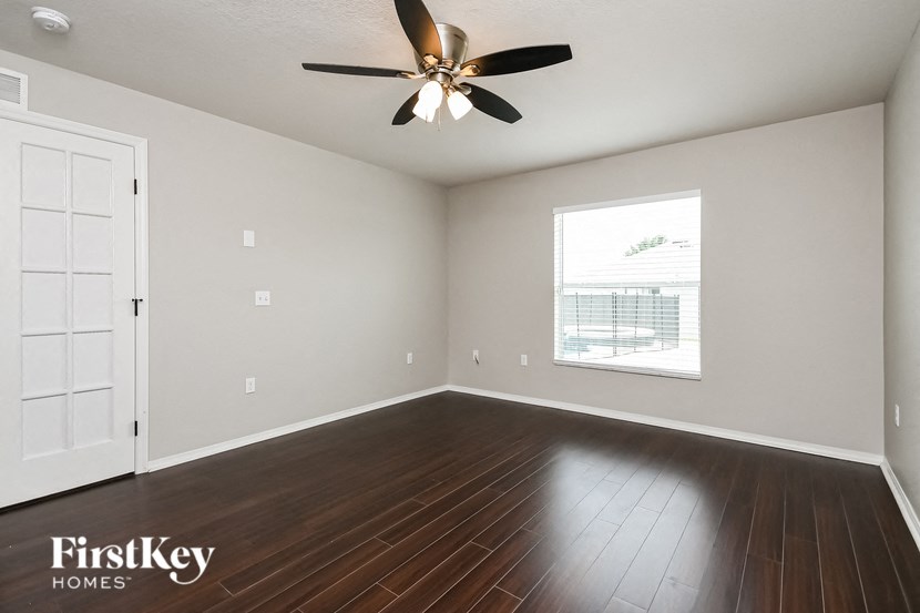 an empty living room with a ceiling fan and a window