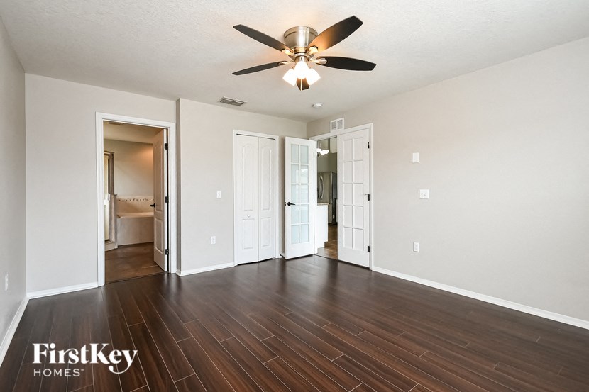 an empty living room with wood flooring and a ceiling fan