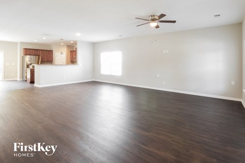 A spacious room with wooden flooring and a ceiling fan.