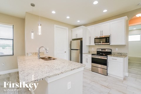 a white kitchen with stainless steel appliances and a marble counter top