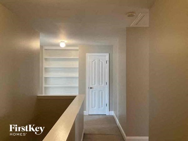 a hallway with white shelves and a white door