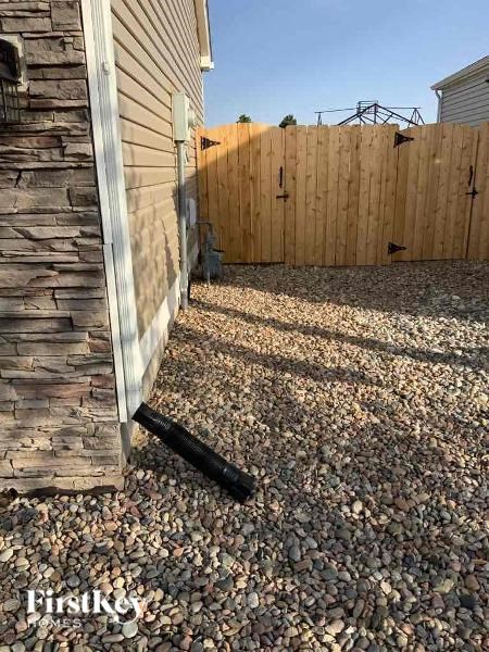 a backyard with a wooden fence and a pebble ground