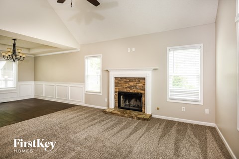 A spacious living room with a fireplace and a carpeted floor.