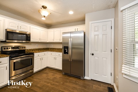 A kitchen with a stainless steel refrigerator and white cabinets.
