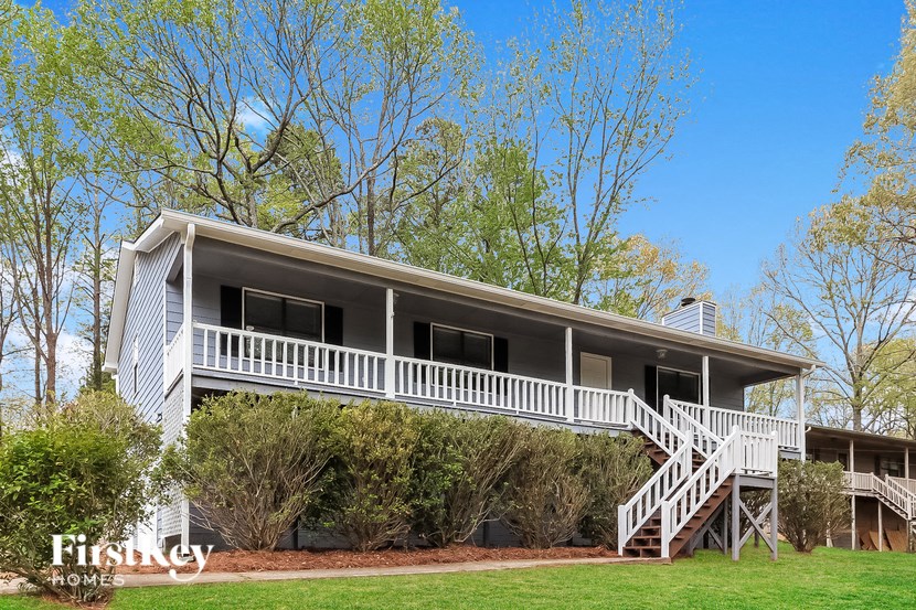 A white house with a balcony and stairs leading to the second floor.