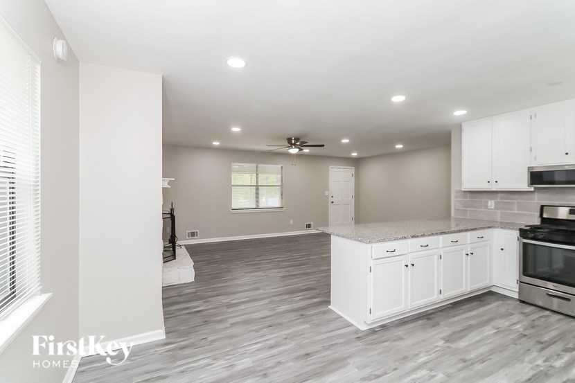 A spacious kitchen with white cabinets and a grey floor.
