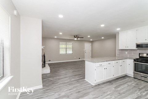 A spacious kitchen with white cabinets and a grey floor.