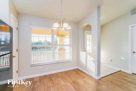 an empty dining room with a large window and a door to a hallway