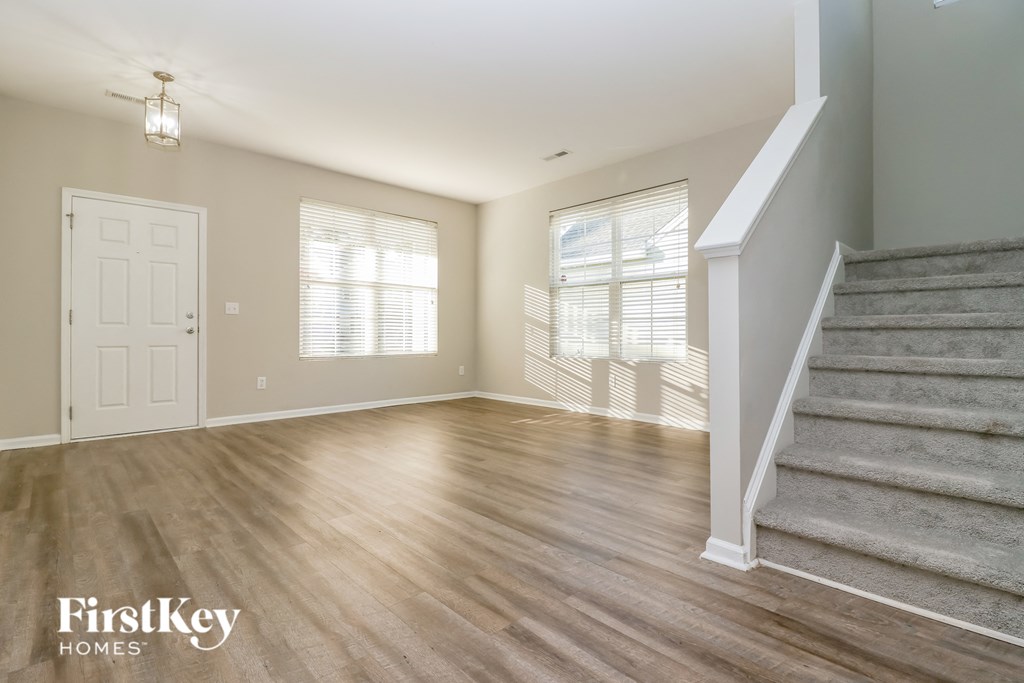an empty living room with stairs and a door to a room with a staircase