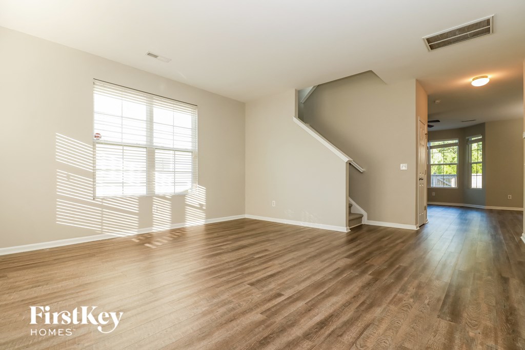 an empty living room with hardwood floors and a staircase