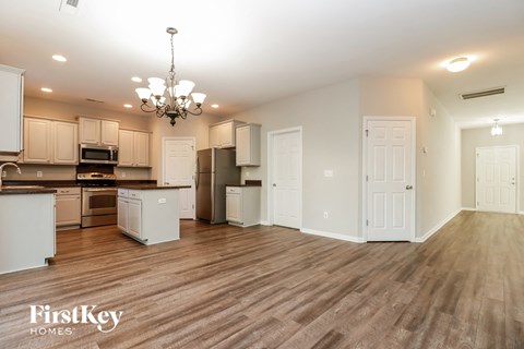 a kitchen and living room with a wood floor and white cabinets