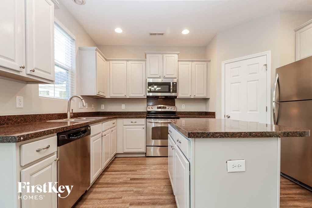 a kitchen with white cabinets and granite counter tops and stainless steel appliances