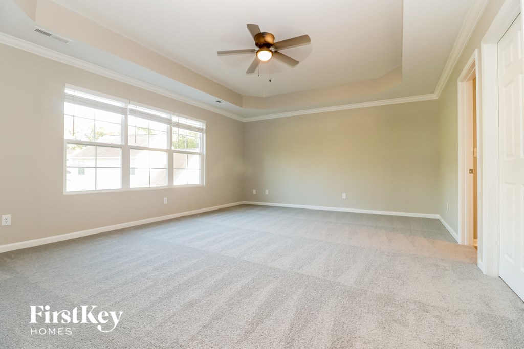 an empty living room with a ceiling fan and a window