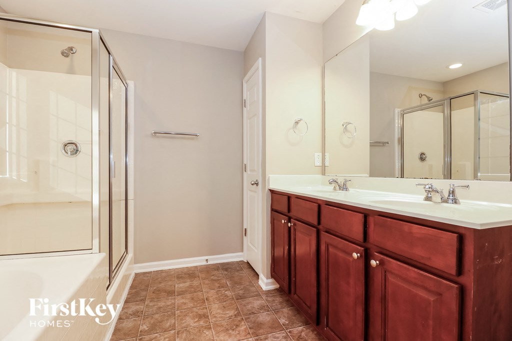 a master bathroom with two sinks and a shower
