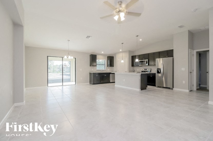 an empty kitchen and living room with a ceiling fan