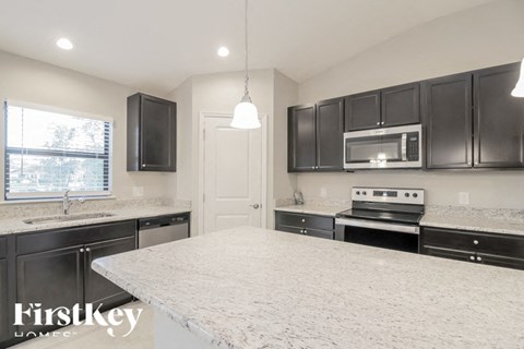 a kitchen with black cabinets and a marble counter top