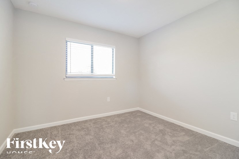a bedroom with a window and a carpeted floor