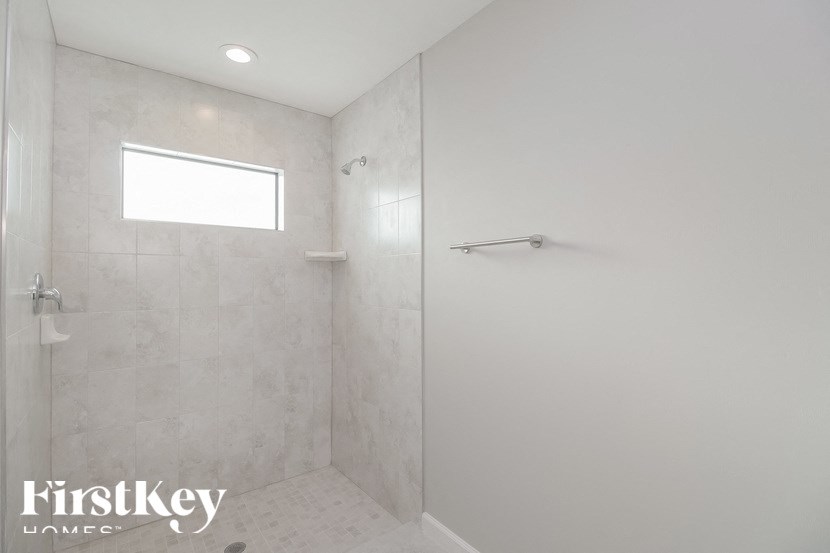 a white bathroom with a shower and a window in it