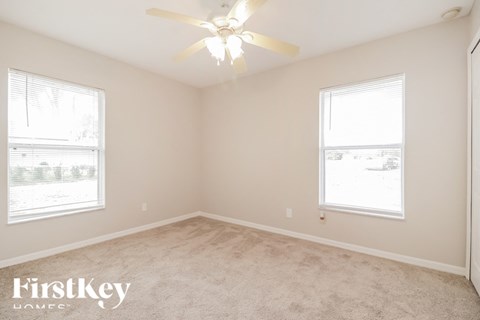 a bedroom with a ceiling fan and two windows