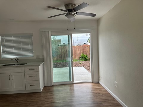 A kitchen with a sink, cabinets, and a ceiling fan.