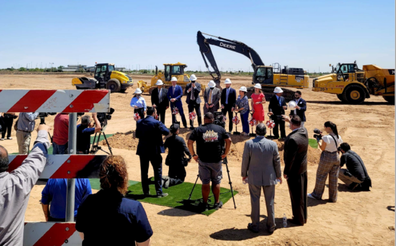 a crowd of people standing around a group of excavators