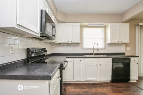 a kitchen with white cabinets and black counter tops and a sink