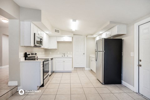 a kitchen with white cabinets and white appliances and a black refrigerator