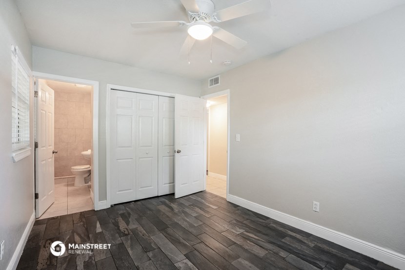 a bedroom with a white door and a ceiling fan