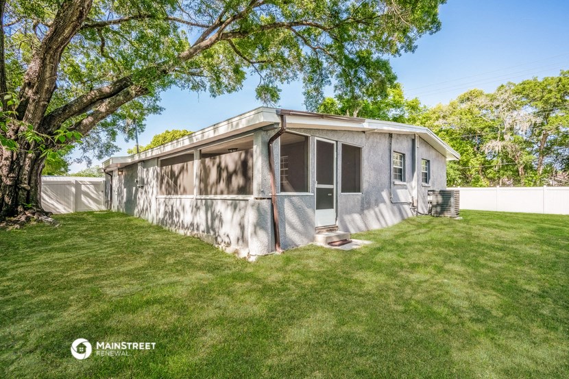 a small gray house in a backyard with a tree