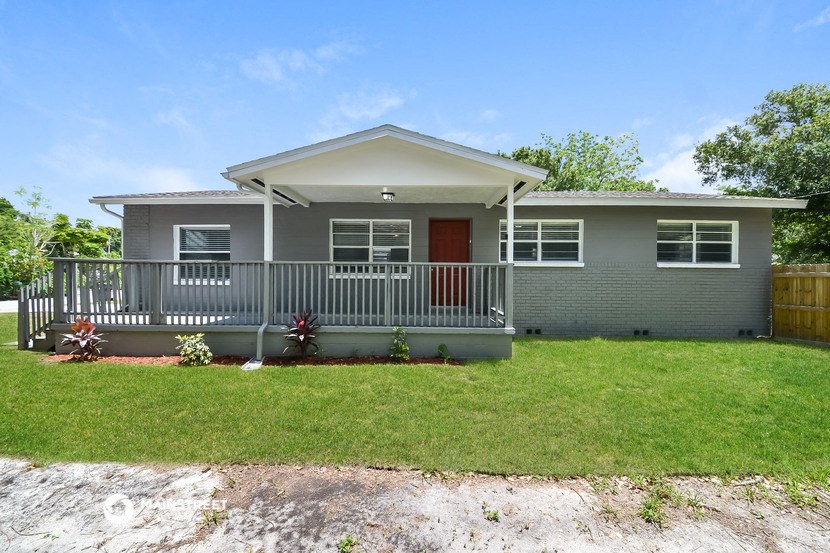 a small gray house with a porch and a lawn