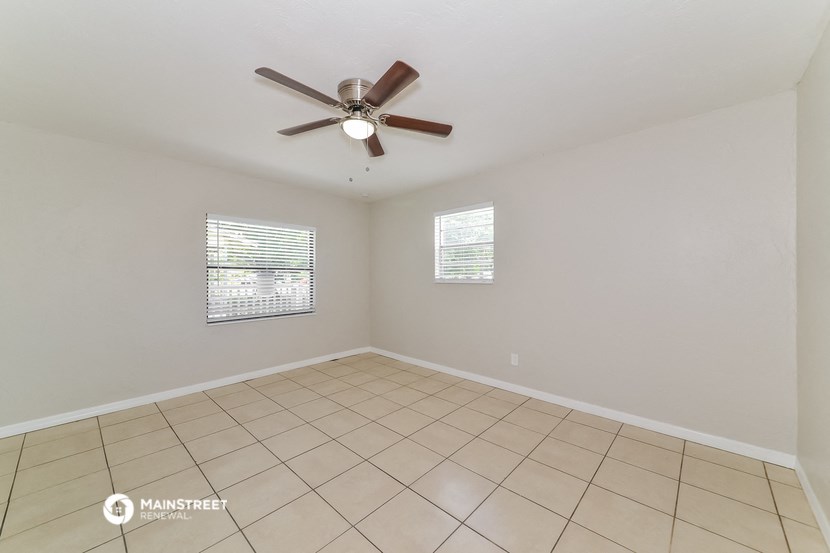 an empty living room with a ceiling fan and a tiled floor