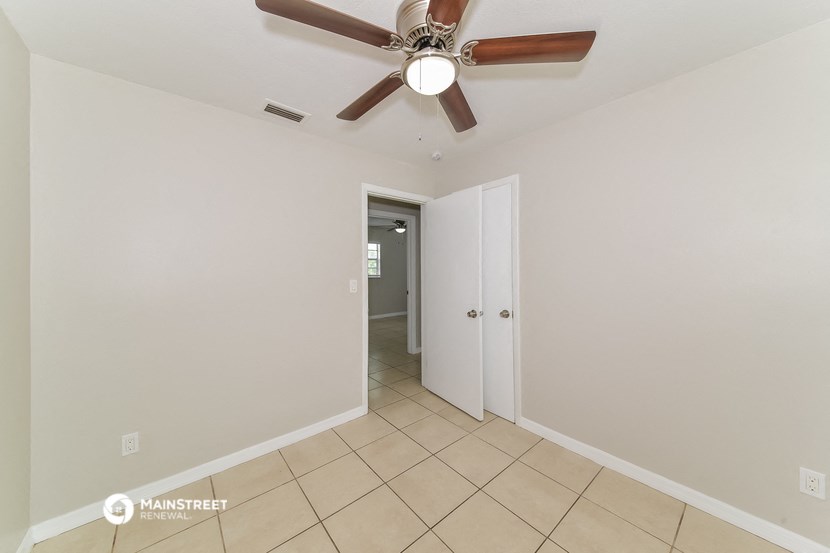 a living room with a ceiling fan and a door to a hallway