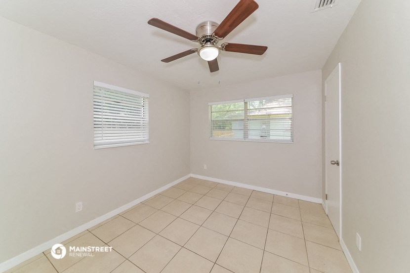 an empty living room with a ceiling fan and a tiled floor