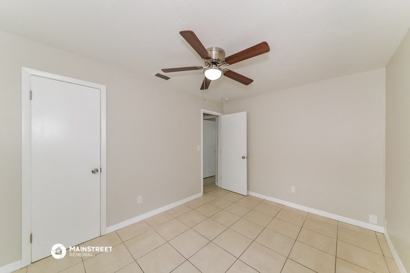 a living room with a ceiling fan and a tiled floor