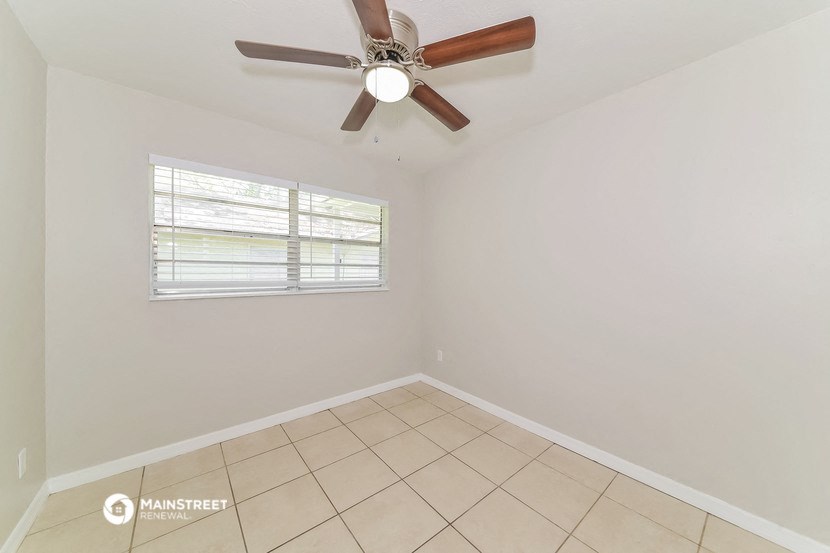 an empty room with a ceiling fan and a window