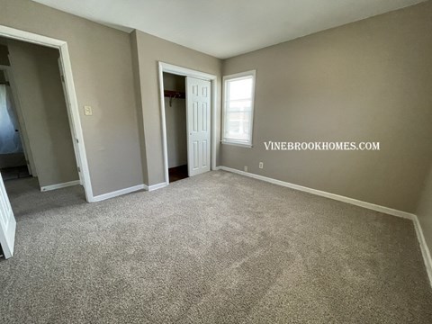 a living room with carpet and a door to a closet