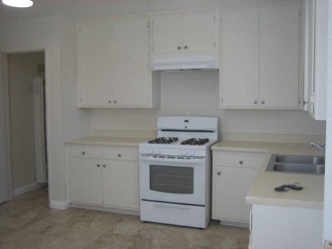 A white kitchen with a stove and cabinets.