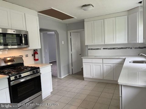 A kitchen with white cabinets and a black stove top.